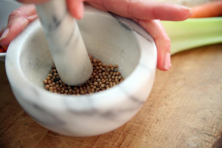coriander being crushed in a marble mortar