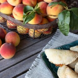 basket of peaches next to a basket of peach empanadas