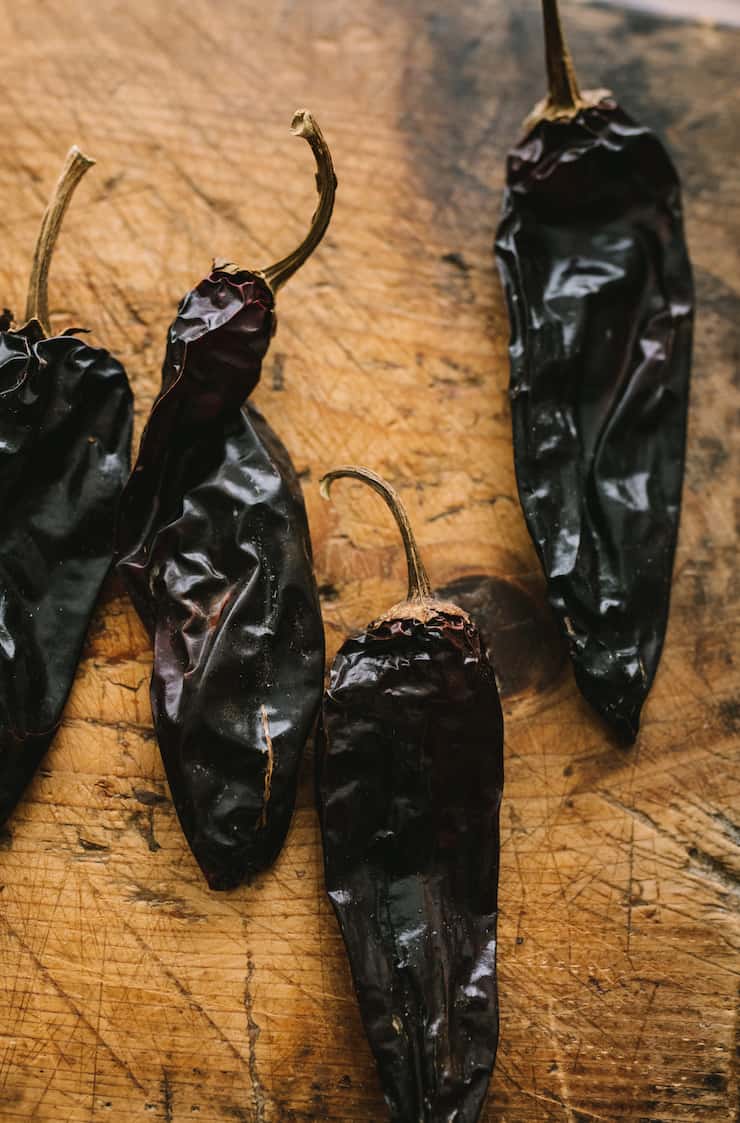 dried Mexican chilis on a rough wooden surface