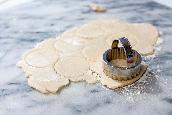 short bread cookie dough and round cookie cutter on marble