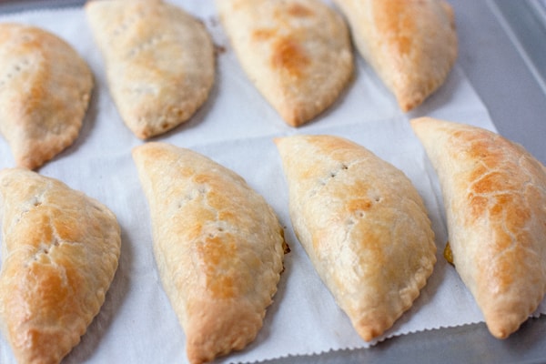 baked green Chile empanadas turnovers on a parchment sheet on baking sheet