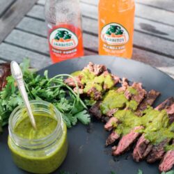Grilled Skirt Steak with Chimichurri Sauce with two bottles of Jarritos on a wooden table