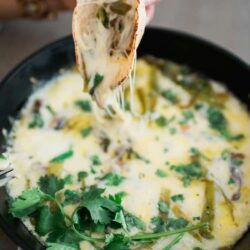 hand holding tortilla filled with queso fundido with hatch chiles and mushrooms