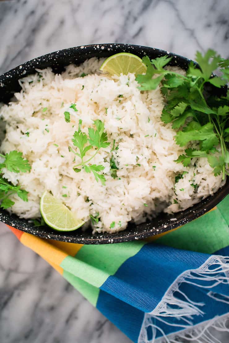 Cilantro lime rice in a speckled black bowl on a colorful tapestry