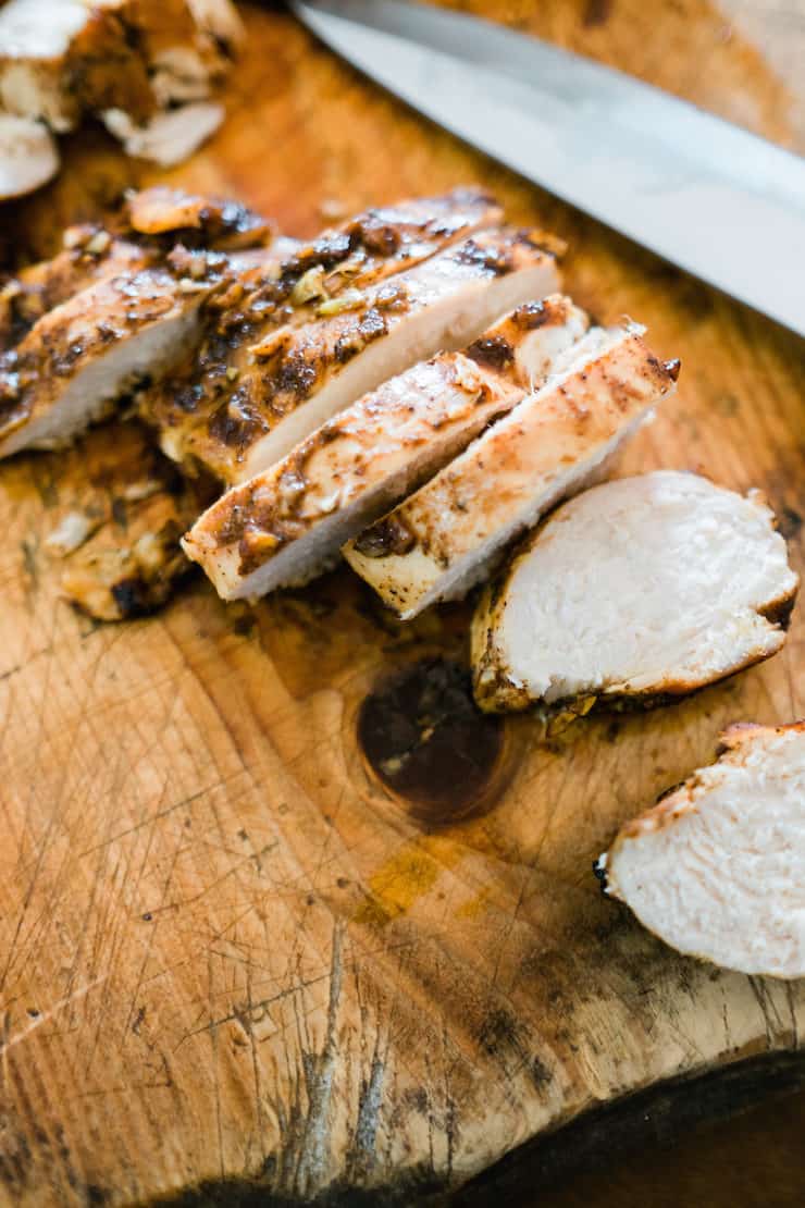 Close up slices of oven baked chicken breasts on a wooden board