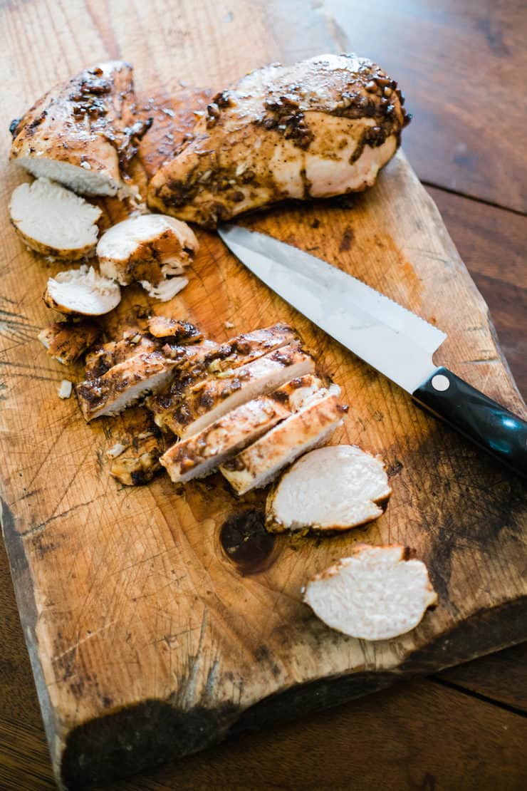 Oven Baked chicken breasts sliced on a wooden board