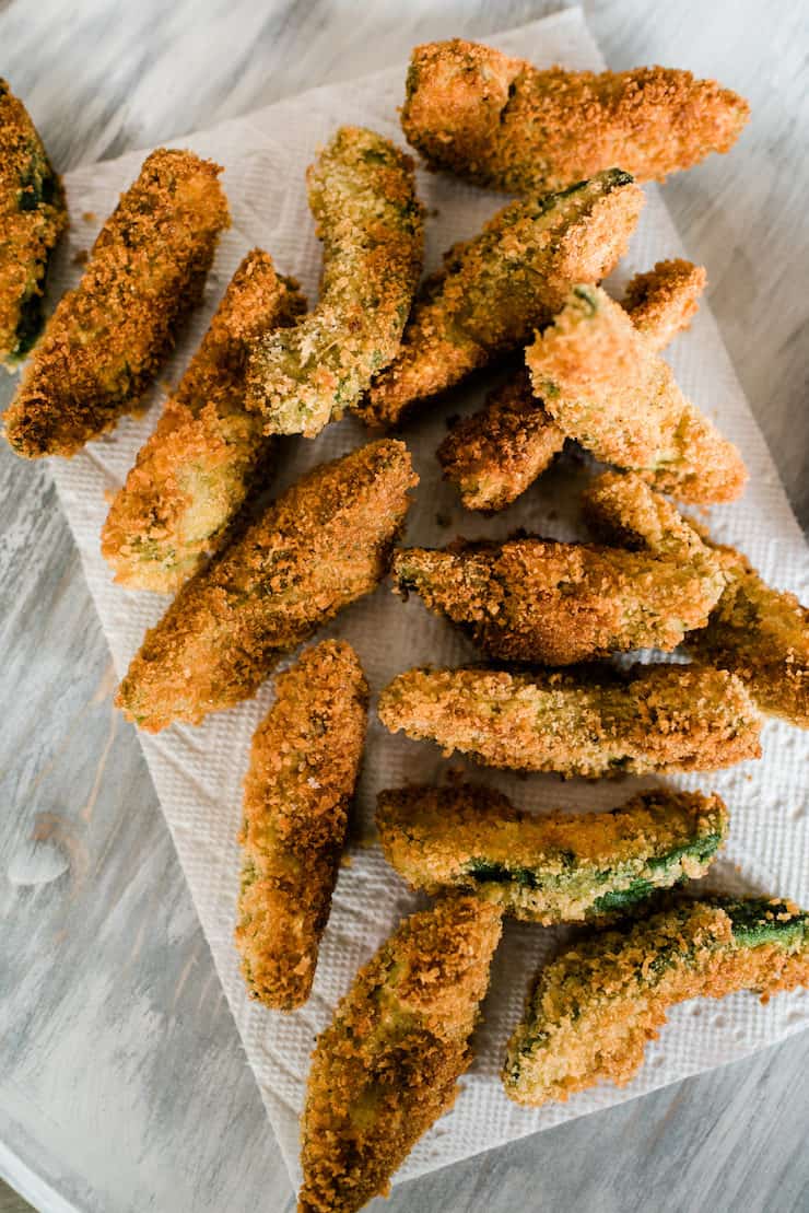 overhead shot of a pile of panko crusted fried avocado slices draining on paper towels