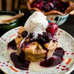 45 degree angle shot of bourbon bread pudding topped with berry sauce and vanilla ice cream
