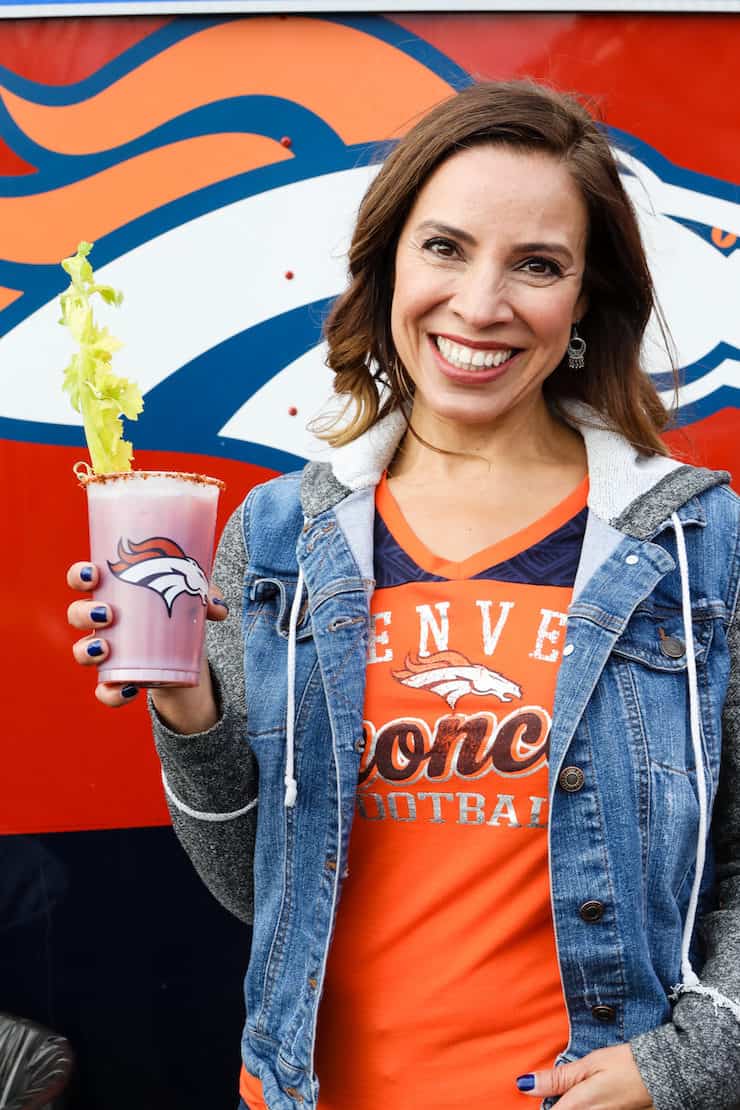 Latina food blogger holding a Bloody Mary at NFL Denver Broncos tailgate