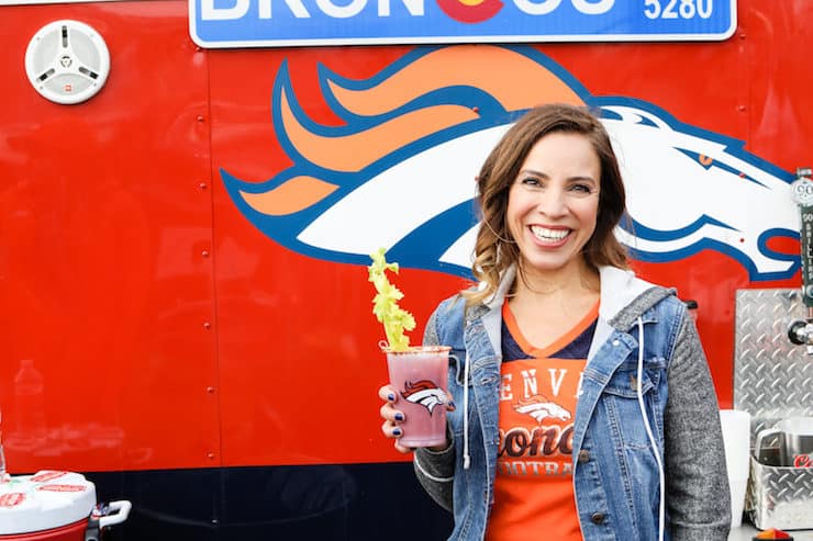 Latina food blogger Yvette Denver Broncos tailgate holding a Bloody Mary 