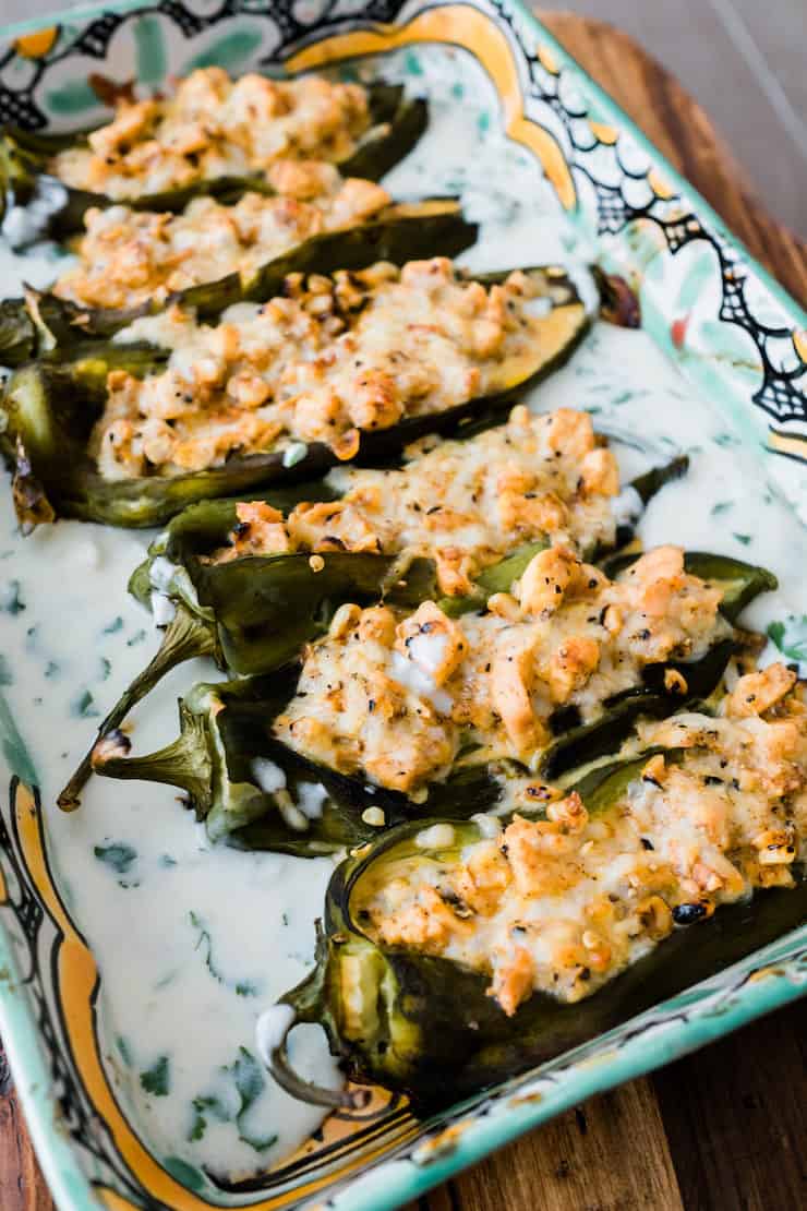 Chicken Stuffed Chiles Rellenos in a colorful Talavera baking dish after baking in a cilantro cream sauce 