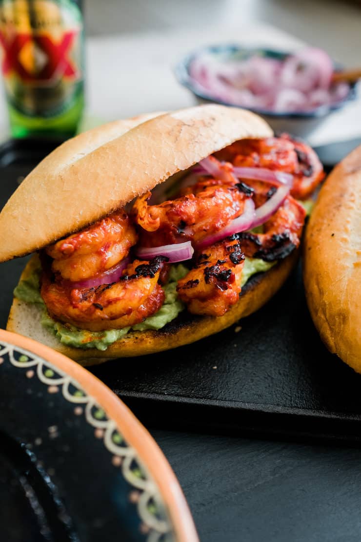 close up shot of Mexican spicy shrimp po' boy with pickled red onions and avocado mash