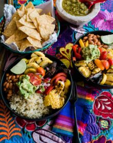 two plated burrito bowls on a colorful tapestry lined table