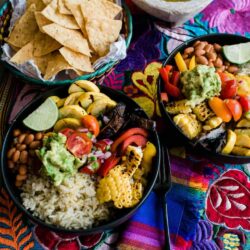 two plated burrito bowls on a colorful tapestry lined table