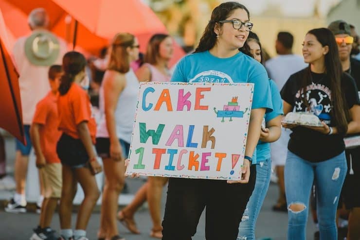 young girl holding a sign for a cake walk