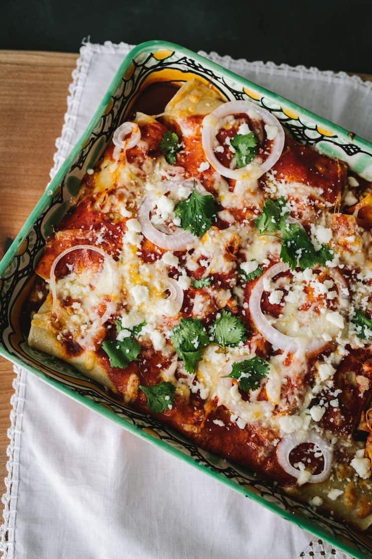Black Bean & Rice Enchiladas rolled in a casserole dish baked and sprinkled with Queso fresco and cilantro