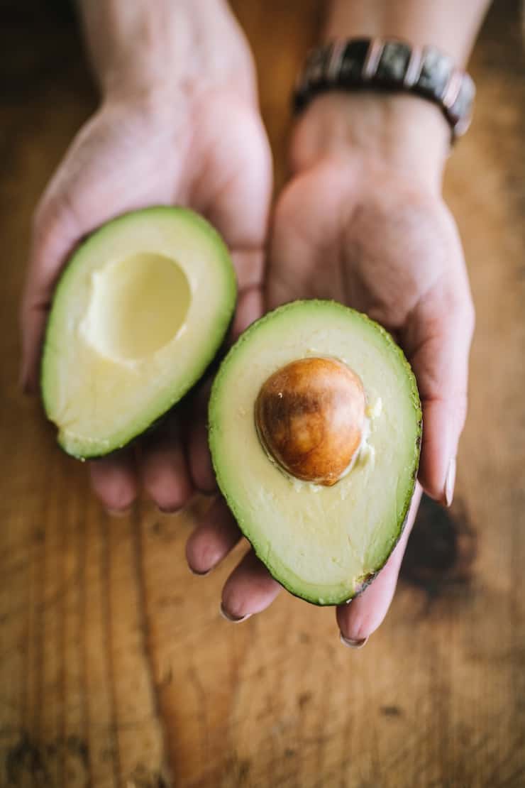 holding a cut avocado in half