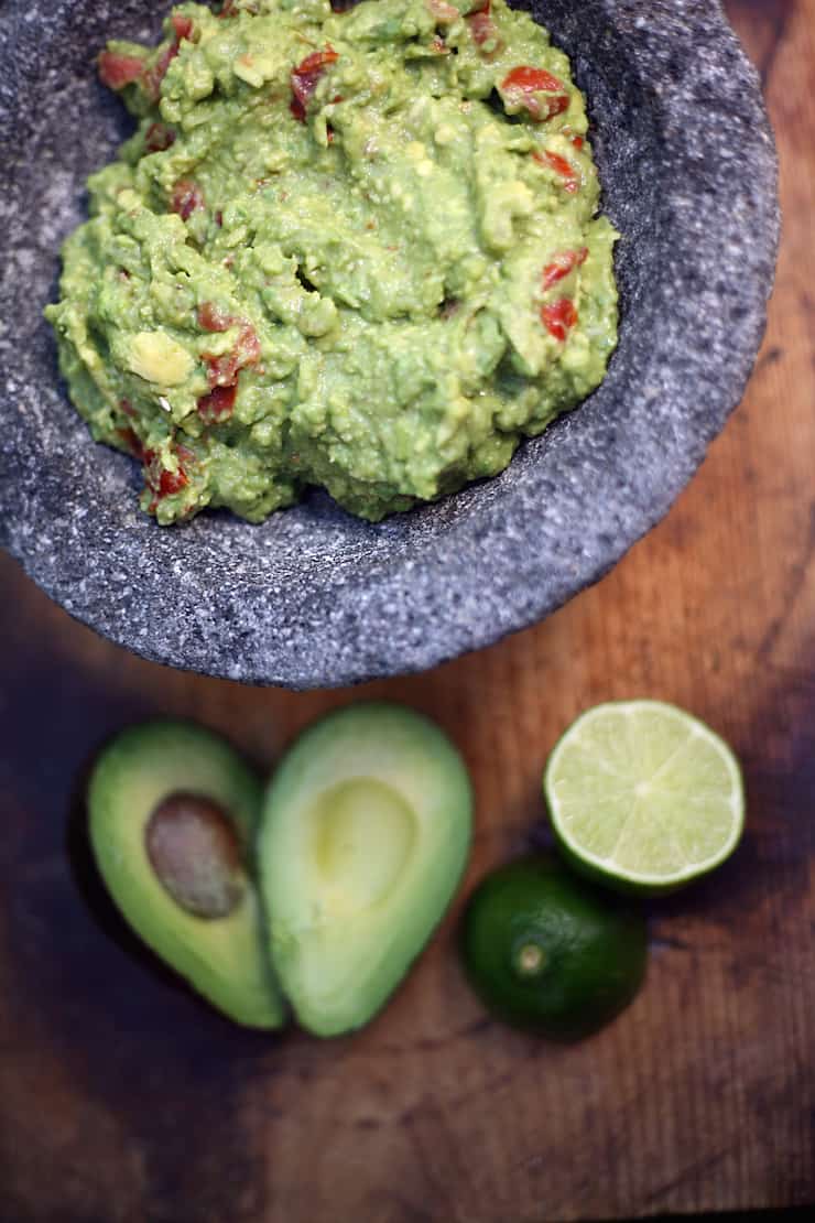 guacamole in a Molcajete with avocados and limes