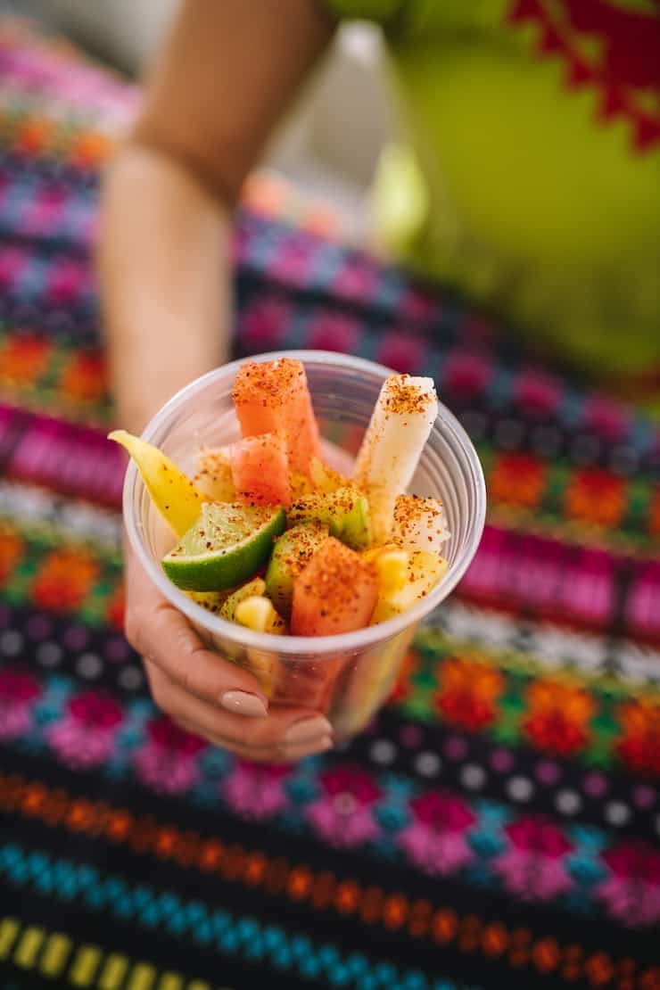 holding a Mexican fruit cup on a colorful textile