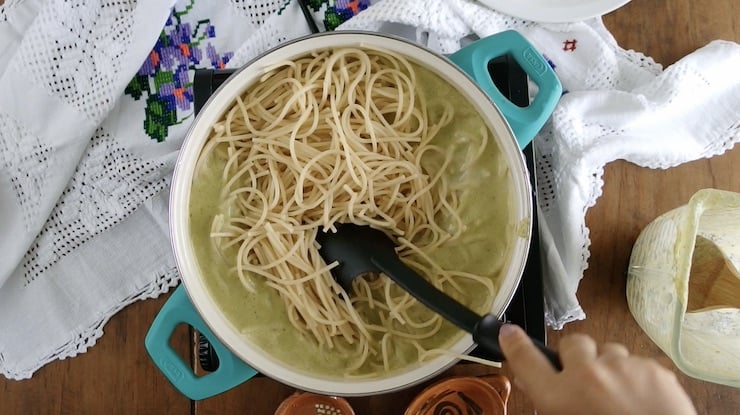 tossing cooked creamy poblano sauce with spaghetti.