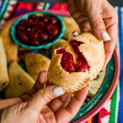 hand breaking a cherry empanada in half to show the filling
