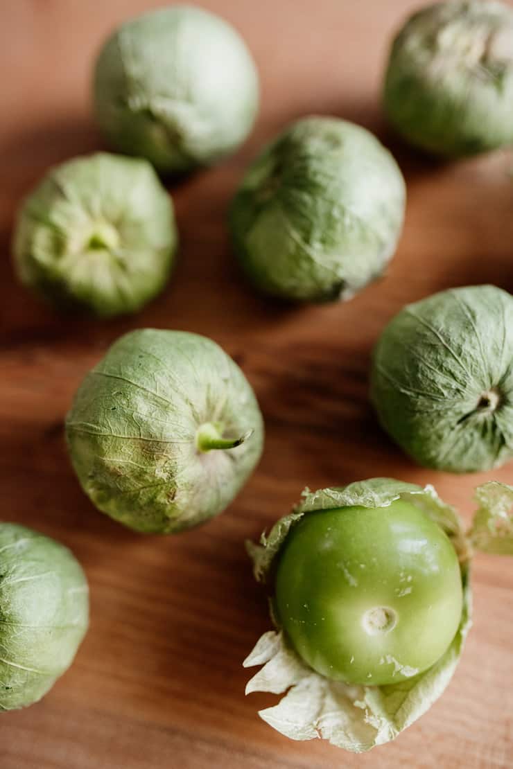 tomatillos in their husks on a wooden surface
