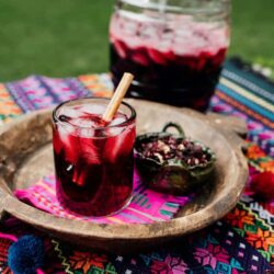 Agua de Jamaica or Hibiscus Tea served in a glass with a big jar next to the tray