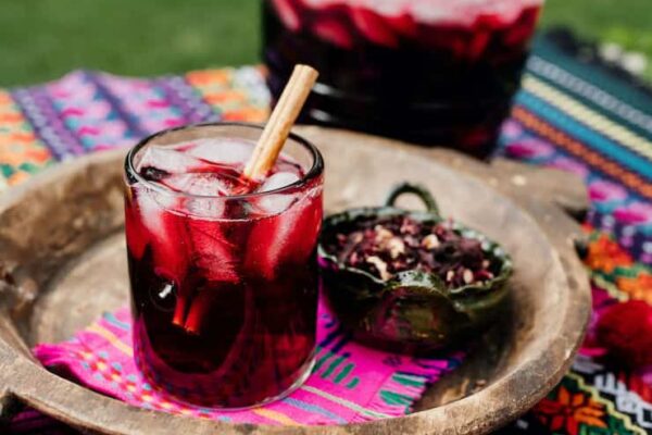 Agua de Jamaica or Hibiscus Tea served in a glass with a big jar next to the tray