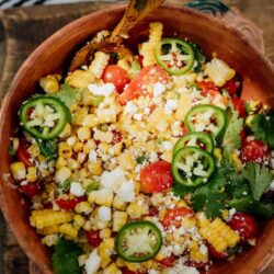 Mexican Street Corn Salad ready and served in a big bowl on a wooden board