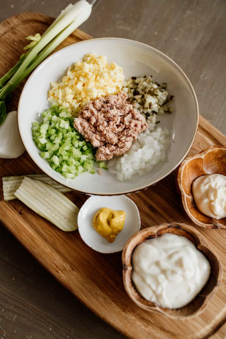 ingredients prepped to make tuna salad: tuna mustard yogurt mayo onion eggs pickles celery