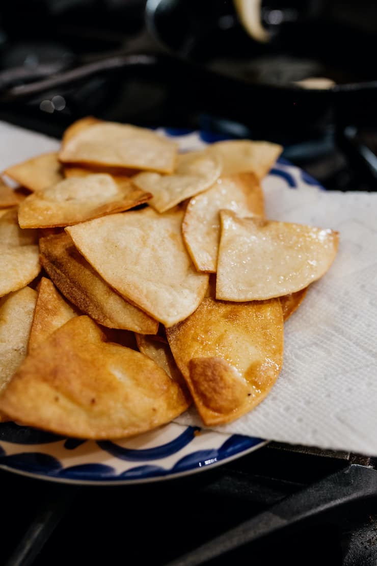 pile of homemade tortilla chips draining on a paper towel