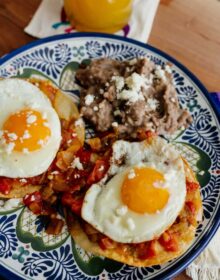 plate of huevos rancheros with a side of refried beans on a blue and white plate