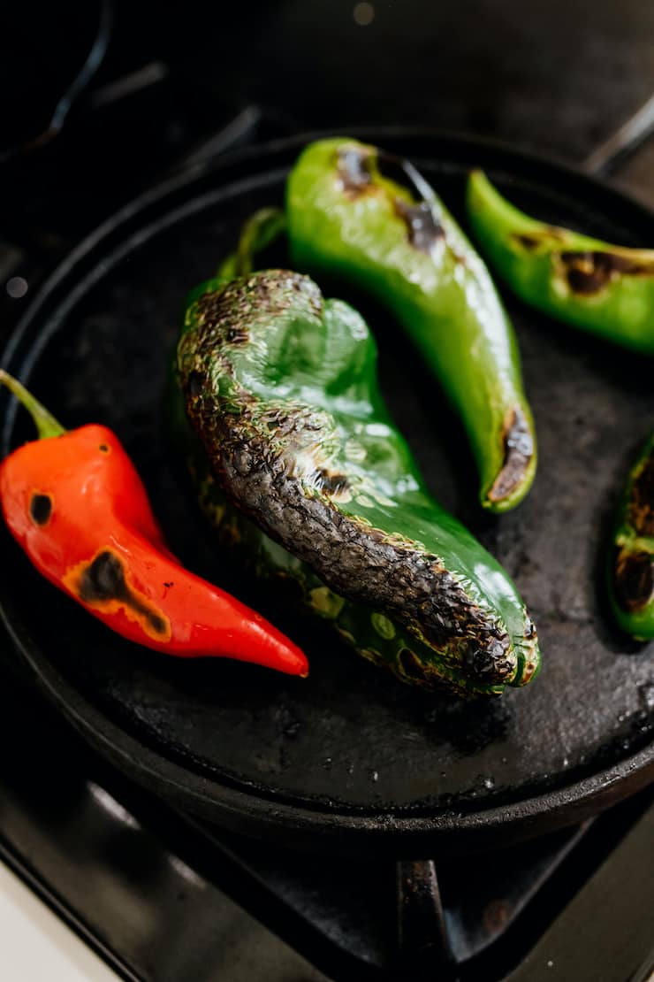 assorted Mexican chiles roasting in a cast iron pan