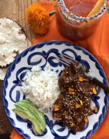 chicken mole on a blue and white plate with white rice and salted avocado