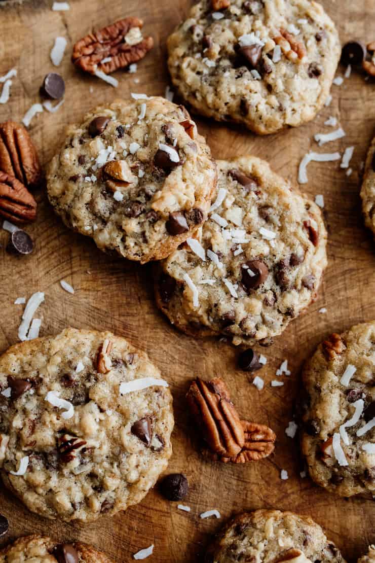 cowboy cookies on a wooden cutting board with pecans, coconut and chocolate chips