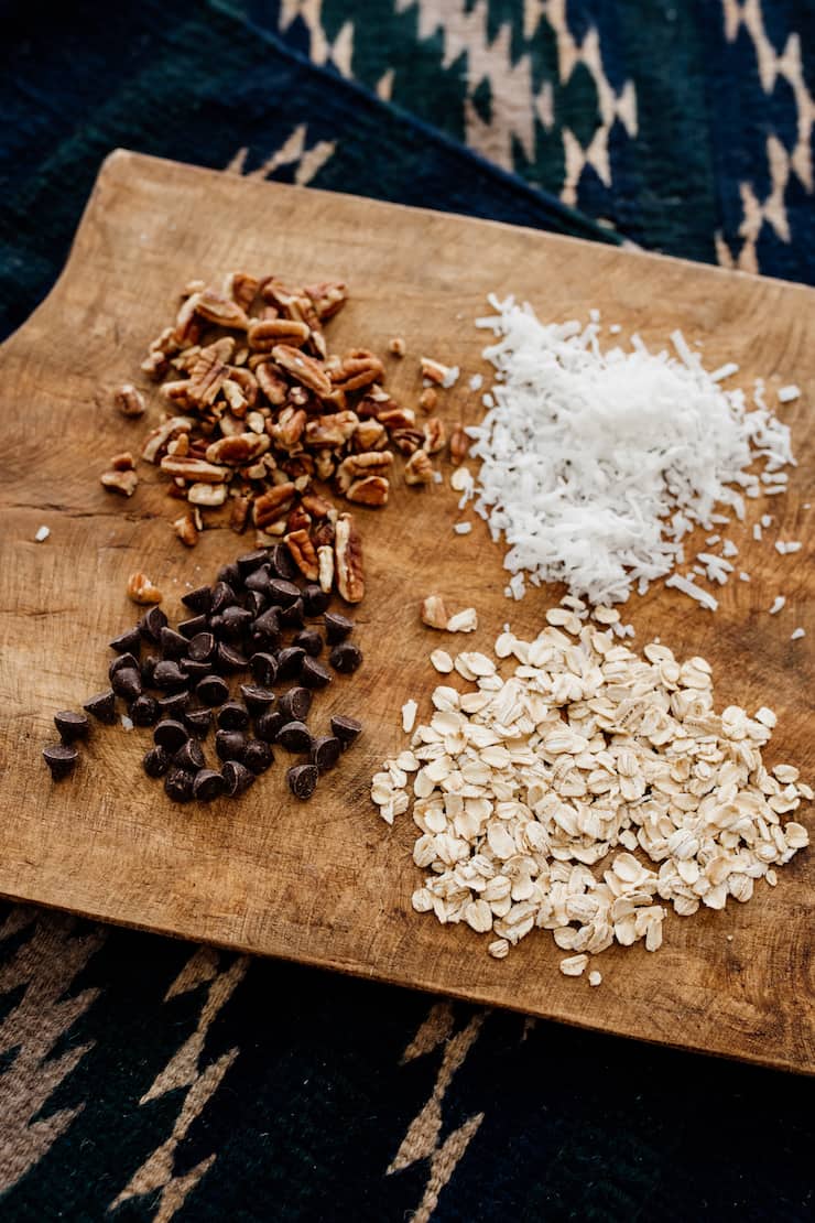 pecans, chocolate chips, oats and shredded coconut on a wooden cutting board