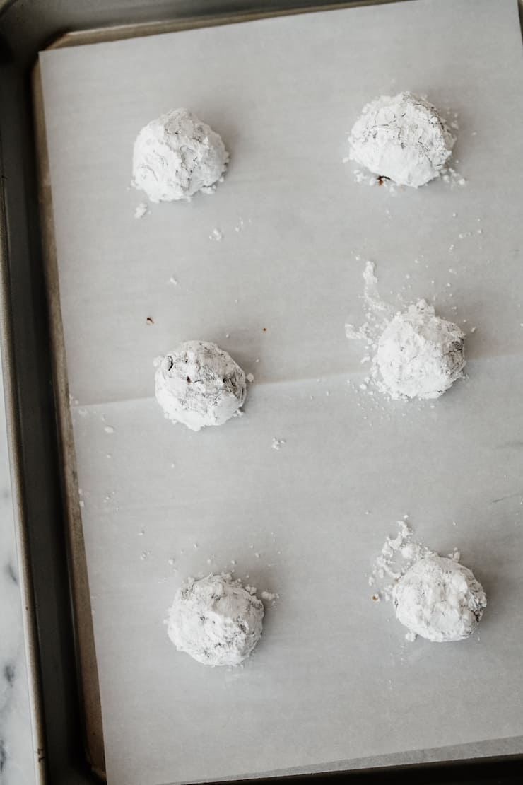 mexican chocolate crinkle cookie dough balls on a parchment lined cookie sheet