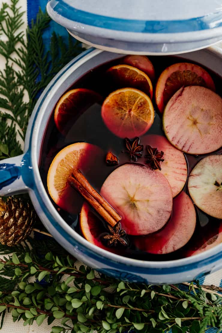 spiced mulled wine in a blue and white punch bowl with floating slices of oranges, apples, whole star anise and cinnamon sticks