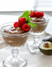 vegan mexican chocolate avocado mousse in footed crystal glasses with raspberries and mint