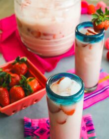 pitcher and two glasses filled with homemade strawberry horchata and garnished with strawberries