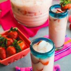 pitcher and two glasses filled with homemade strawberry horchata and garnished with strawberries