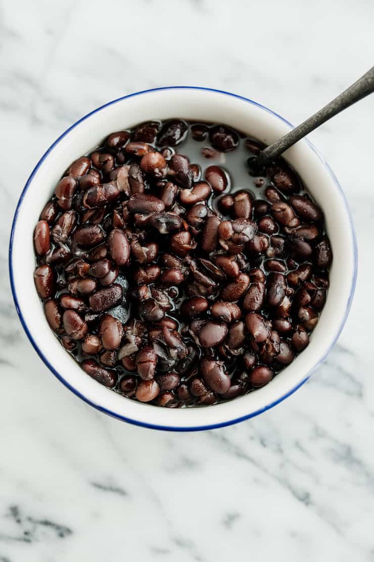 overhead shot of instant pot black beans in a white bowl with a blue rim and a silver fork