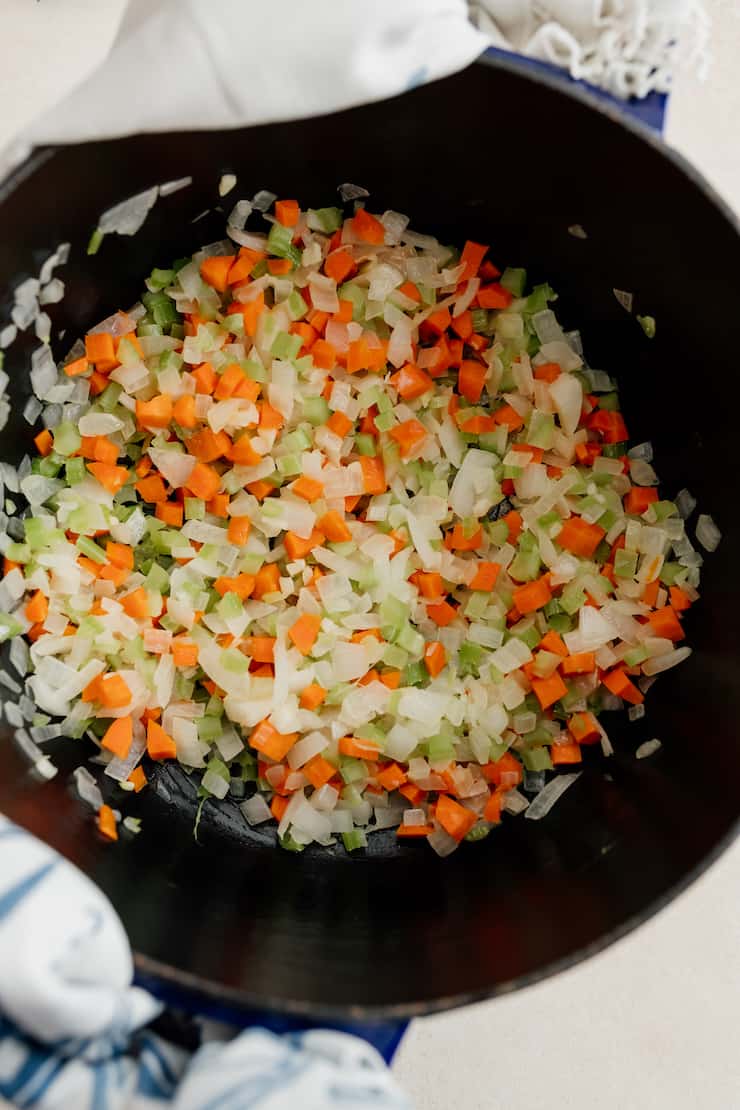 carrots and celery added to onions sautéing in pot