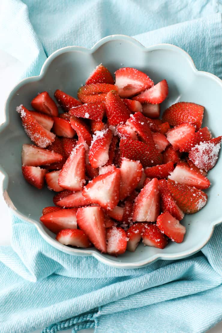 strawberries tossed with truvia to macerate in a turquoise bowl
