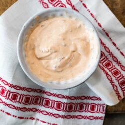 creamy chipotle sauce in a white bowl on a white and red patterned tea towel