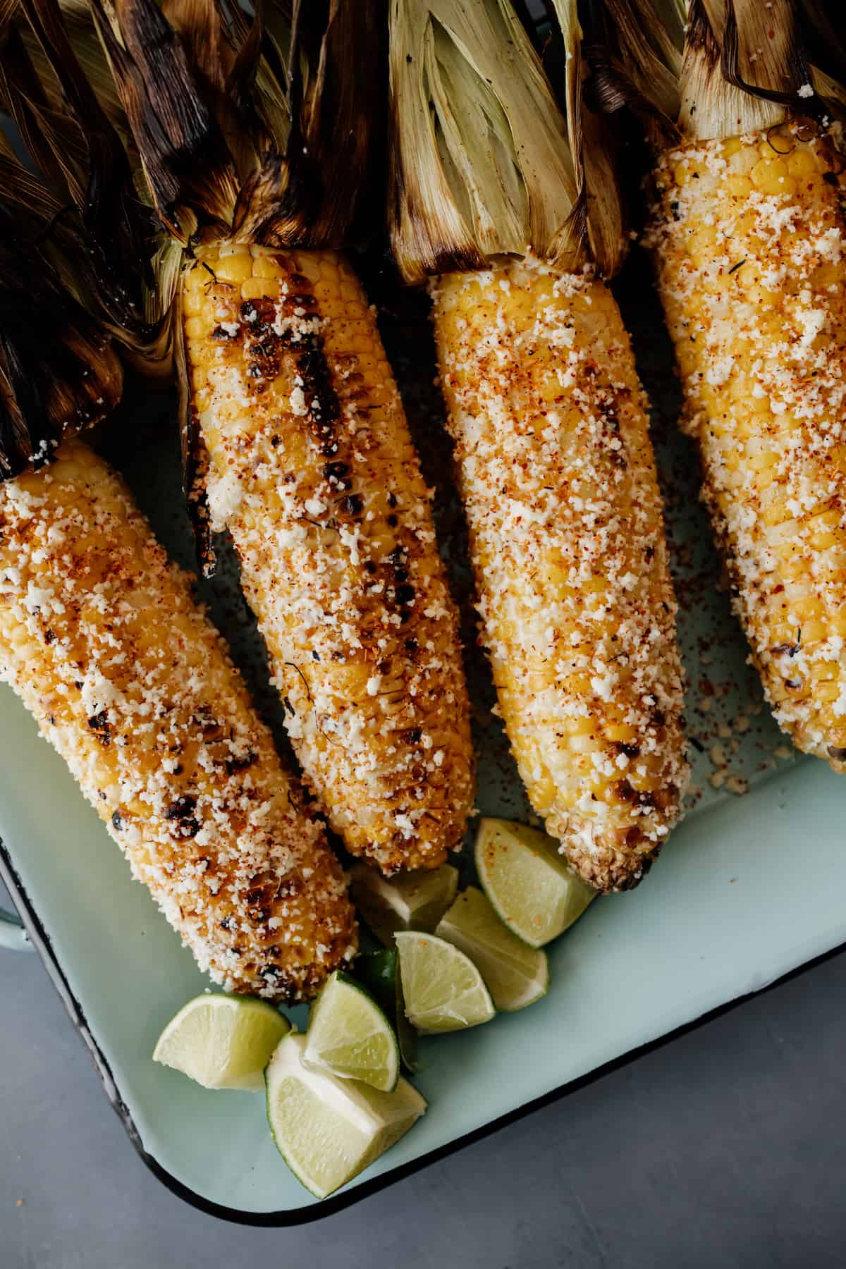4 pieces of Mexican street corn on a serving platter.