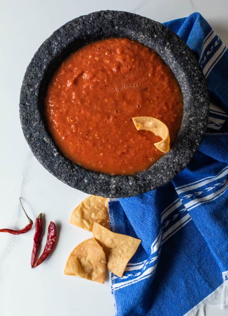 overhead shot of chile de arbol salsa in a stone mortar with some tortilla chips to the side