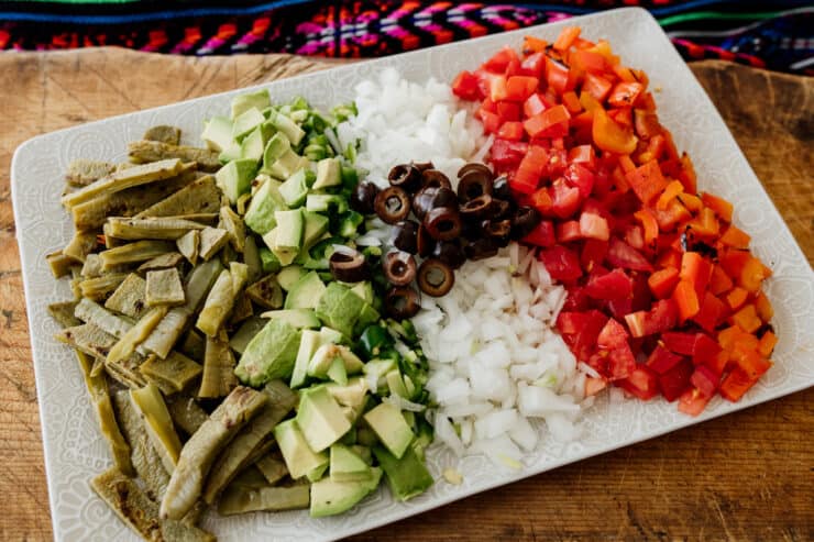 green white and red chopped ingredients on a white plate symbolizing Nopales a la Mexicana