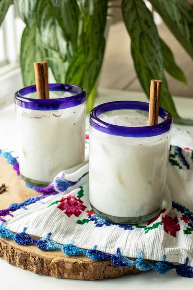 two glasses of horchata on a wooden serving tray with embroidered napkins
