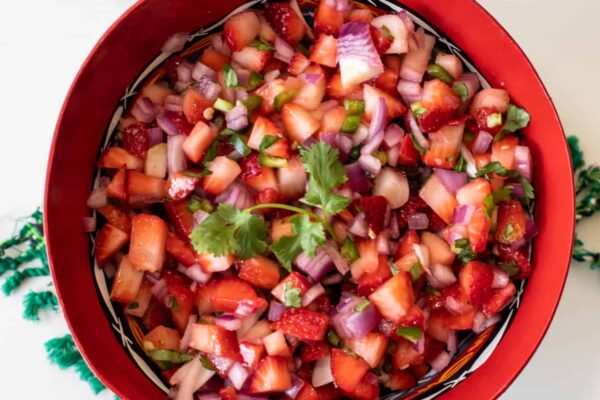 overhead shot of a red bowl filled with strawberry salsa